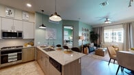 This single-floor residence is designed with a cohesive contemporary aesthetic, characterized by soft sage-green accent walls, light wood-tone flooring, and a carefully curated neutral palette throughout. The open-concept kitchen anchors the living space, featuring two-tone cabinetry pairing white upper cabinets with warm wood lower cabinets, granite countertops, stainless steel appliances including a full-size refrigerator, gas range, and microwave, and a central island with bar seating illuminated by industrial-style pendant lights. The kitchen flows naturally into the living area, which benefits from large windows and a sliding glass door that invite natural light and outdoor views. A ceiling fan and ample wall space add comfort and character to the living room. The dedicated dining area accommodates a round marble-topped table with upholstered seating. Two bedrooms are present, one featuring a deep green accent wall and the other offering an exterior-facing window with outdoor views. The bathroom includes a granite vanity, soaking tub, and shower combination. A hallway connects the private areas, completing the functional and stylish layout.