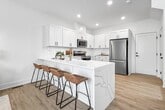This contemporary residence in West Des Moines offers 1720 square feet of thoughtfully designed living space across three floors. The home boasts 3 bedrooms and 4 bathrooms, including a generous 230 square foot primary suite. The main level showcases an open-concept layout, combining the kitchen and living area for seamless entertainment and daily living.

The gourmet kitchen features sleek white cabinetry, stainless steel appliances, and ample counter space, perfect for culinary enthusiasts. The living room is bathed in natural light from large windows and offers a cozy yet modern ambiance with its neutral color palette and stylish furnishings.

Each bedroom is well-appointed, with the primary bedroom boasting a canopy bed and ample space for additional furniture. The bathrooms are elegantly designed, featuring modern fixtures and a glass-enclosed shower in at least one of them.

The home includes a dedicated laundry room with stacked washer and dryer units, maximizing space efficiency. Additional amenities include a garage, utility room, and multiple closets for storage. The property's three levels are connected by staircases, ensuring easy navigation throughout the home.

With its blend of functionality and contemporary design, this West Des Moines property offers a comfortable and stylish living environment for its occupants.