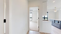 This thoughtfully designed 2-bedroom, 2-bathroom residence offers a bright, contemporary living experience across a single floor. The open-concept kitchen serves as the heart of the home, showcasing white shaker cabinetry with gold hardware, a crisp quartz countertop, and a striking two-tone center island in slate blue with a built-in microwave. Stainless steel appliances — including a gas range with a stainless hood, refrigerator, and dishwasher — are complemented by a white subway tile backsplash and a gold-finished faucet. Globe pendant lights with brass accents add a refined touch overhead. Light wood-look flooring flows throughout the main living areas, while large black-framed windows invite abundant natural light into the open living space, which also features access to a private balcony. Both bedrooms are carpeted and include ceiling fans and oversized black-framed windows with outdoor views. The primary bedroom offers a generous footprint with its own closet. The bathrooms are finished with white cabinetry, quartz countertops, black hardware accents, and wood-look tile flooring. Two closets and a dedicated hallway round out this well-appointed, modern residence.