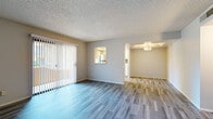This single-floor residence offers a clean, functional layout designed for comfortable everyday living. The spacious living area is anchored by wide-plank wood-style flooring and features a large sliding glass door dressed with vertical blinds, flooding the room with natural light. A pass-through window connects the living space to the kitchen, enhancing the open feel of the floor plan.

The galley-style kitchen is well-equipped with stainless steel appliances, including a refrigerator and electric range, complemented by white cabinetry, light countertops, a subway tile backsplash, and a double-basin sink. A narrow window above the countertop brings in additional natural light and outdoor views.

The two bedrooms feature plush carpeting, neutral-toned walls, and windows that overlook the surrounding exterior. One bedroom includes a sliding-door closet with built-in shelving, providing practical storage. The textured ceilings carry throughout the sleeping areas, consistent with the rest of the home.

The bathrooms are finished with wood-style tile flooring, white vanity cabinetry, and clean countertops. One bathroom features a well-lit vanity mirror with bright overhead lighting, while the other offers a straightforward layout with efficient use of space. Together, these rooms create a cohesive, move-in-ready living environment.