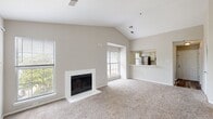 Located at 1623 Parkridge Cir in Crofton, Maryland, this single-floor residence offers a well-designed layout with notable architectural character throughout. The living area is a standout feature, boasting soaring vaulted ceilings that create an airy, open atmosphere. A classic white-surround fireplace serves as the focal point of the room, complemented by plush wall-to-wall carpeting and multiple windows that draw in abundant natural light. The open pass-through to the kitchen maintains a connected feel between living and dining areas. The kitchen is equipped with stainless steel appliances, including a refrigerator, range, and over-the-range microwave, set against a crisp white subway tile backsplash and light-toned cabinetry with modern hardware. Wood-look flooring adds a warm, durable finish to the kitchen space. The primary bedroom is generously proportioned with vaulted ceilings, a louvered closet, an en-suite area, and sliding glass doors opening to a private balcony overlooking lush greenery. An additional bedroom features a large window framing views of mature trees, and is finished with soft carpeting. The bathroom includes a full tub-shower combination with tile surround, a single vanity with ample counter space, and wood-look flooring that ties the space together cohesively.