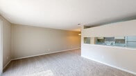 Located at 5300 Woodruff Farm Rd in Columbus, GA, this one-bedroom, one-bathroom unit offers a practical and comfortable single-floor layout. The open-concept living and dining area is generously sized, featuring warm neutral-toned carpet, clean white walls, and a large sliding glass door dressed with vertical blinds that floods the space with natural light and provides outdoor views. A pass-through opening connects the living area to the kitchen, which is outfitted with a galley-style design featuring wood-look flooring, dual-toned laminate countertops, cream cabinetry with ample storage, a double-basin sink, an electric range, a dishwasher, and a full-size refrigerator. A chandelier pendant light accents the adjacent dining area. The bedroom offers a comfortable retreat with plush carpeting, a ceiling fan with light fixture, a window for natural light, and convenient access to a dedicated closet. The full bathroom includes a combined tub and shower unit with clean white surrounds, a toilet, and matching wood-look flooring that ties the space together cohesively. Overall, the unit presents a clean, functional living environment well-suited for individuals or couples seeking straightforward, move-in-ready accommodations.