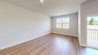 Located at 1096 Darrowby Ridge Cir in Burlington, NC, this three-story home offers four bedrooms and four bathrooms thoughtfully distributed across its floors. The ground level features a garage with a concrete floor and utility connections, providing practical storage and parking. The main living level showcases an open-concept kitchen and living room with light hardwood flooring. The kitchen is equipped with crisp white shaker cabinets, stainless steel appliances including a refrigerator, range, and over-the-range microwave, plus a double sink — all finished with clean, modern hardware. The living area flows seamlessly, bathed in natural light. A convenient half bathroom with hardwood-style flooring is also found on this level. The upper floor hosts the bedrooms, including a generously sized primary suite complete with a dual-sink vanity featuring white cabinetry and matte black fixtures, a glass-enclosed walk-in shower, and direct access to a carpeted bedroom with natural light. Additional bedrooms are carpeted and bright, each with windows offering outdoor views. Closets throughout feature wire shelving systems for organized storage. Neutral tones, clean lines, and consistent finishes create a cohesive, move-in-ready aesthetic throughout the home.