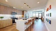 Located at 4098 Hillsboro Pike in Nashville's desirable Green Hills neighborhood, this modern 2-bedroom, 2-bathroom residence offers a thoughtfully designed open-concept layout with high-end finishes throughout. The living area is anchored by dramatic floor-to-ceiling windows that flood the space with natural light and frame sweeping views of the Nashville skyline, creating a bright and airy atmosphere. Wide-plank hardwood flooring flows seamlessly from the living area into the kitchen, which features warm wood cabinetry, a marble-inspired tile backsplash, stainless steel appliances, and a large waterfall-edge island with bar seating — ideal for both cooking and entertaining. Both bedrooms are generously proportioned with elevated ceilings that enhance the sense of space, and each includes its own dedicated closet. The primary bathroom is particularly well-appointed, offering a double vanity with wood cabinetry, large-format tile flooring, and a glass-enclosed walk-in shower. The second bathroom mirrors the same refined aesthetic with a walk-in shower and a sleek single vanity. Two well-sized closets provide ample storage. Clean lines, neutral tones, and contemporary fixtures throughout lend the residence a cohesive, sophisticated character.