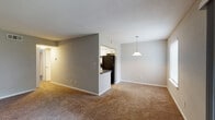 This single-floor residence at 37 Treeview Dr in Lithonia, Georgia offers a thoughtfully laid-out living space with a warm, neutral palette throughout. The expansive living room is finished with plush carpeting and neutral-toned walls, with natural light flowing in through a large window and sliding glass doors that open onto a covered balcony overlooking lush greenery — an inviting extension of the interior living space. A pendant light anchors the adjacent dining area, which connects seamlessly to the kitchen via a pass-through opening. The kitchen is well-appointed with white shaker-style cabinetry, dark countertops, a stainless steel sink with a modern faucet, and black appliances including a refrigerator and electric range. The bedrooms are generously sized, each featuring soft carpeting, neutral gray walls, and ample natural light from multiple windows. The bathroom showcases a clean, updated design with white cabinetry, dark countertops, a large vanity mirror, and wood-look flooring. Textured ceilings are found throughout, adding character to the overall aesthetic. The floor plan flows efficiently, making this a comfortable and functional home in the Lithonia community.