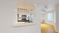 This single-floor residence offers a thoughtfully arranged layout with 2 bedrooms, 3 bathrooms, a kitchen, and a dedicated closet. The open-concept living area is anchored by warm hardwood flooring that flows throughout the home, complemented by crisp white walls that create a bright, clean aesthetic. A ceiling fan with a brushed nickel finish adds both function and character to the living space.

The kitchen is a standout feature, designed with a pass-through arched opening that connects it seamlessly to the living area. It is equipped with stainless steel appliances including a range, microwave, and refrigerator, alongside white upper cabinetry, dark lower cabinets with black hardware, and a white countertop with an undermount sink fitted with a modern black spring-neck faucet. Track lighting illuminates both the kitchen and adjacent living spaces.

The bedrooms are comfortable and well-lit, with natural light filtering in through windows fitted with blinds. The primary bedroom includes a walk-in closet with built-in wire shelving for organized storage. The bathrooms maintain the home's modern aesthetic, featuring clean white vanities, bold black-framed mirrors, and vessel sinks. Consistent hardwood-style flooring extends into the bathrooms, tying the design together cohesively throughout the entire residence.
