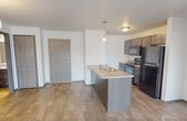 This 790 square foot apartment offers a thoughtful layout that maximizes space efficiency. The single-floor design features two bedrooms and two full bathrooms, making it ideal for small families or roommates. The heart of the home is an open-concept living area that seamlessly integrates the kitchen and dining space. The modern kitchen boasts sleek dark wood cabinetry, black appliances, and a generous island with a light-colored countertop, perfect for meal preparation or casual dining.

The flooring throughout the main living areas is a durable wood-look material, while the bedrooms are comfortably carpeted. Each bedroom offers ample space and is equipped with a window, providing natural light and ventilation. The bathrooms feature clean, white fixtures and tiled floors, with at least one including a bathtub-shower combination.

A notable convenience is the in-unit laundry room, complete with a washer and dryer set and overhead shelving for storage. The apartment's neutral color palette, primarily in whites and light grays, creates a bright and airy atmosphere throughout. Lighting is well-distributed, with a mix of recessed ceiling lights and pendant fixtures. The overall design prioritizes functionality and comfort in a compact urban living space.