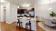 Located at 2020 Proximity Dr in Charleston, SC, this single-floor, 2-bedroom, 2-bathroom residence offers a thoughtfully designed layout with a cohesive, neutral aesthetic throughout. Warm hardwood flooring flows seamlessly across all main living areas, complementing the clean white walls and creating an inviting atmosphere.

The kitchen is a standout feature, boasting rich dark cabinetry, granite countertops, a large island with a double stainless steel sink, pendant lighting, and stainless steel appliances. It opens naturally to a dedicated dining area, which is accented by an elegant pendant light. The living room is bright and comfortable, with natural light streaming through slatted blinds.

The spacious primary bedroom features multiple windows with sheer curtains, a ceiling fan, and generous closet space with built-in wire shelving. The second bedroom is equally well-lit, with large windows offering views of greenery. Both bathrooms are finished with dark wood vanities, white countertops, and framed mirrors.

A dedicated laundry room with side-by-side washer and dryer units and wire shelving adds everyday convenience. A central hallway connects all areas efficiently, completing this well-organized and practical Charleston residence.