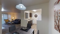 This single-floor residence offers a functional and comfortable layout across several well-defined living spaces. The living room serves as a welcoming centerpiece, featuring a tile-surround fireplace, plush carpeting, and a sliding glass door that fills the room with natural light and provides access to an outdoor area. Adjacent to the living room, the dining area is illuminated by a stylish pendant light and connects seamlessly to the kitchen through an open pass-through design. The kitchen is equipped with dark espresso cabinetry, light countertops, a full suite of white appliances including a refrigerator, dishwasher, and coil-burner range, and tile flooring that extends through the dining space. The bedrooms are carpeted and offer a calm retreat, each featuring windows that bring in natural light and views of surrounding greenery. One bedroom includes a standard closet with built-in rod and shelf storage. The full bathroom is finished with tile flooring, a single-sink vanity with dark cabinetry, and a tub-shower combination. A dedicated in-unit laundry room houses a full-size washer and dryer along with overhead shelving for additional storage. Neutral wall tones and consistent finishes throughout create a cohesive and inviting atmosphere.