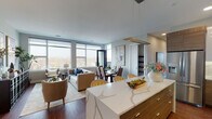 This thoughtfully designed single-floor residence showcases a seamless open-concept layout that connects the kitchen, dining, and living areas into one cohesive, light-filled space. Large floor-to-ceiling windows line the main living areas, flooding the interior with natural light while framing expansive outdoor views of the surrounding landscape.

The kitchen is a standout feature, centered around a generously sized waterfall-edge quartz island with striking veining. Cabinetry combines high-gloss white uppers with warm wood-toned lowers, complemented by a matching quartz backsplash, an undermount sink, and stainless steel appliances, creating a clean, contemporary aesthetic.

The dining area accommodates a glass-top table with upholstered seating and benefits from direct access to an outdoor balcony, reinforcing the connection between interior and exterior. The living room is anchored by a neutral palette, rich hardwood flooring, and curated art, with a corner window arrangement that maximizes views.

The bedroom is a serene retreat with a large picture window overlooking the balcony and a well-appointed walk-in closet with built-in shelving and dual hanging rods. The bathroom features a tub-shower combination with clean white tile surround, a floating vanity, and a backlit mirror, delivering a polished, spa-like finish throughout.