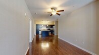 Located at 3245 Glenn McConnell Pkwy in Charleston, SC, this one-bedroom, one-bathroom residence offers a well-designed single-floor layout that maximizes comfort and functionality. The open-concept living and kitchen area forms the heart of the home, where rich, dark hardwood-style flooring extends throughout and a ceiling fan adds a practical touch overhead. The kitchen is a standout feature, outfitted with dark espresso cabinetry, granite countertops, a full suite of stainless steel appliances including a refrigerator with ice maker, range, microwave, and dishwasher, plus a central island with pendant lighting that provides additional prep and casual dining space. Track lighting illuminates the kitchen further, highlighting a decorative lattice cabinet detail. The living area is bright and open, with natural light flowing in from windows dressed with blinds. The spacious primary bedroom features plush carpeting, a ceiling fan, multiple windows for natural light, and access to a dedicated closet. The full bathroom is appointed with a granite-topped vanity, dark cabinetry, and a tub/shower combination with clean white tile surround and hardwood-style flooring. Throughout the space, neutral tones and consistent finishes create a cohesive, move-in-ready feel.