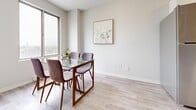 Located at 162 George St in Sarnia, Ontario, this thoughtfully designed 1-bedroom, 1-bathroom unit offers a compact yet functional layout across a single floor. Light wood laminate flooring flows throughout, creating a cohesive and airy feel.

The combined living and dining area serves as the heart of the unit. The dining space accommodates a glass-top table with upholstered chairs and benefits from a large sliding window that frames views of the surrounding cityscape, allowing natural light to fill the room. The living area features a comfortable seating arrangement alongside a dedicated workspace, making the space adaptable for both relaxing and working from home. Wall sconces and carefully placed artwork contribute to a warm, modern ambiance.

The bedroom is a well-sized retreat with a large window offering additional city views. Light-toned walls and wood-style flooring carry through from the main living area, maintaining a consistent aesthetic. Built-in closet storage is also present.

The bathroom is finished with neutral beige tile on both the walls and floor, and includes a full soaker tub with a shower curtain, providing a clean and functional space.

A hallway connects the rooms efficiently, with the overall layout making excellent use of the available footprint. The unit presents a modern, minimalist aesthetic throughout.