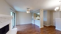 This two-floor residence is designed with a practical and open layout that maximizes living space across its levels. The main living area is anchored by rich wood-look flooring, neutral gray walls, and a textured ceiling, creating a warm and inviting atmosphere. A ceiling fan with a light fixture illuminates the space, while large sliding glass doors allow natural light to flow in and provide access to the outdoors. The living area connects seamlessly to a dedicated dining space, distinguished by an elegant chandelier overhead.

The kitchen features a pass-through design that opens to the living area, promoting an open-concept feel. It is outfitted with gray cabinetry, white quartz countertops, a stainless steel sink with a modern faucet, a white subway tile backsplash, and black appliances including a range, microwave, and dishwasher.

The bedroom is generously sized with plush carpeting, a ceiling fan, and a sliding mirrored closet that offers ample storage. The bathroom is finished with gray cabinetry, a white countertop vanity, and a shower, with an adjacent walk-in closet providing additional storage convenience. The entry area features wood-look flooring and wall sconce lighting, creating a welcoming first impression upon arrival.
