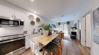 Located at 1212 E 7th Ave. in Tampa's vibrant Ybor City neighborhood, this one-bedroom, one-bathroom residence offers a well-designed, single-story layout that maximizes every square foot. Warm hardwood-style flooring flows throughout, anchoring a bright and cohesive interior.

The open-concept kitchen and living area serves as the heart of the home. The kitchen features white shaker cabinetry, a classic subway tile backsplash, stainless steel appliances including a full-size refrigerator, range, microwave, and dishwasher, and a black matte faucet over a undermount sink. A portable butcher block island with bar seating adds both function and charm. The adjoining living area is filled with natural light from large French doors framed by floor-to-ceiling curtains, creating an inviting atmosphere.

The bedroom is a comfortable retreat, complete with a ceiling fan, natural light from a window with blinds, and a dedicated walk-in closet outfitted with wire shelving and hanging rods. The bathroom offers a refined finish with hexagonal mosaic tile flooring, a white subway tile walk-in glass shower, a white vanity with a framed mirror, and matte black fixtures throughout. Every room reflects a clean, contemporary aesthetic suited for modern living.
