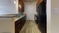 This single-floor residence on Stoney Creek Drive in Fredericksburg, Virginia offers a well-organized layout designed for comfortable everyday living. The entryway transitions from wood-look luxury vinyl flooring into the main living area, which is finished with neutral-toned carpet and features a ceiling fan and French doors leading to a private balcony, allowing natural light to fill the space.

The galley-style kitchen is thoughtfully appointed with rich dark wood cabinetry, granite-look countertops, a stainless undermount sink, and black appliances including a refrigerator and range. Wood-look flooring runs throughout the kitchen, contributing to a cohesive aesthetic.

The bedrooms are generously sized, each featuring plush carpet and windows with blinds that provide views of the surrounding community. The rooms offer ample wall space and connect seamlessly to the rest of the unit via paneled interior doors.

Two bathrooms serve the residence. One includes a soaking tub and wood-look flooring, while the other features a vanity with dark wood cabinetry, a large mirror, and well-lit overhead fixtures. Both bathrooms maintain a clean, neutral palette consistent with the overall design of the home.