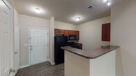 Located at 7744 Woodspring Dr in Burlington, North Carolina, this single-floor unit offers a well-designed, functional layout ideal for comfortable everyday living. The kitchen is outfitted with warm-toned wood cabinetry, dark countertops, wood-look vinyl flooring, and a full suite of black appliances including a refrigerator, range, microwave, and dishwasher. A peninsula counter provides additional workspace and serves as a natural divider between the kitchen and the open living area. The living room is generously proportioned, featuring neutral carpet flooring, soft neutral wall tones, and a window that invites natural light. The layout connects seamlessly to hallways leading to the bedrooms and bathrooms. The bedrooms are carpeted and finished in neutral tones, with windows offering outdoor views. Two full bathrooms serve the unit, each featuring a vanity with wood-toned cabinetry, a single-sink countertop, a toilet, and a tub-shower combination with a curtain rod or sliding rail. Wood-look flooring in the bathrooms complements the overall design palette. Throughout the unit, clean white trim and consistent neutral finishes create a cohesive and move-in-ready aesthetic.