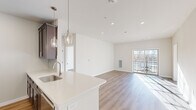 Located at 4550 Falmer Dr in Bethlehem, PA, this two-bedroom, one-bathroom residence offers a thoughtfully designed single-floor layout with modern finishes throughout. The open-concept kitchen and living area serves as the heart of the home, featuring dark-toned shaker cabinetry, white quartz countertops, a stainless steel undermount sink, and a full suite of stainless steel appliances. Elegant pendant lighting hangs above the peninsula, which flows seamlessly into the bright and airy living room. Warm hardwood-style flooring runs throughout the entire unit, lending a cohesive and contemporary feel. The living room is bathed in natural light from a sliding glass door that opens to a private balcony with outdoor views. The spacious primary bedroom includes a ceiling fan, a large window with exterior views, and ample natural light. The second bedroom is equally bright, with a generous window overlooking the outdoors. The full bathroom features a tub-shower combination with brushed nickel fixtures and hardwood-style flooring. Recessed lighting, clean white walls, and a neutral color palette complete the polished, move-in-ready aesthetic of this well-appointed residence.