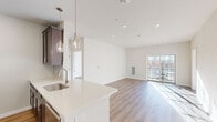 Located at 4550 Falmer Dr in Bethlehem, PA, this two-bedroom, one-bathroom residence offers a thoughtfully designed single-floor layout with modern finishes throughout. The open-concept kitchen and living area serves as the heart of the home, featuring dark-toned shaker cabinetry, white quartz countertops, a stainless steel undermount sink, and a full suite of stainless steel appliances. Elegant pendant lighting hangs above the peninsula, which flows seamlessly into the bright and airy living room. Warm hardwood-style flooring runs throughout the entire unit, lending a cohesive and contemporary feel. The living room is bathed in natural light from a sliding glass door that opens to a private balcony with outdoor views. The spacious primary bedroom includes a ceiling fan, a large window with exterior views, and ample natural light. The second bedroom is equally bright, with a generous window overlooking the outdoors. The full bathroom features a tub-shower combination with brushed nickel fixtures and hardwood-style flooring. Recessed lighting, clean white walls, and a neutral color palette complete the polished, move-in-ready aesthetic of this well-appointed residence.