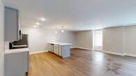 Located at 65 S. Washington Ave in Columbus, Ohio, this single-floor residence offers a thoughtfully designed open-concept layout that seamlessly connects the kitchen, dining, and living areas. Warm hardwood-style flooring extends throughout the main living spaces, creating a cohesive and inviting atmosphere.

The kitchen is a standout feature, equipped with sleek gray shaker-style cabinetry, white quartz countertops, a classic subway tile backsplash, and a full suite of stainless steel appliances including a range, microwave, refrigerator, and dishwasher. A central island with pendant lighting above provides additional prep space and serves as a natural gathering point within the open floor plan.

The expansive living area benefits from recessed lighting and neutral-toned walls, offering a clean and versatile canvas. A windowed door provides access to natural light and connects the space to the exterior. The bathroom is finished with coordinating gray cabinetry, a white quartz vanity top, and a full tub-shower combination with white tile surround. A generously sized walk-in closet with wire shelving and carpet flooring provides ample storage. Throughout, the design reflects a modern aesthetic with practical, high-quality finishes.