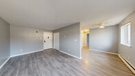 Located at 1650 10th Ave in Newport, MN, this two-bedroom, one-bathroom unit offers a practical and well-organized single-floor layout. The interior features a consistent neutral gray color palette and light wood-look flooring that flows throughout the main living areas, creating a cohesive and clean aesthetic. The living room is a generous, open space filled with natural light from multiple windows and is equipped with a ceiling fan. Baseboard heating and wall-mounted air conditioning units provide year-round climate control. The galley-style kitchen is efficiently designed with white cabinetry, granite-look countertops, and white appliances including a refrigerator and range, offering ample storage and prep space. A hallway connects the main living areas to the two bedrooms and the full bathroom. The primary bedroom is spacious, featuring plush carpeting, a ceiling fan, and multiple windows that bring in natural light and outdoor views. The second bedroom also offers carpeting and a window overlooking the surrounding neighborhood. The bathroom is clean and functional, featuring a tiled mosaic floor, a white vanity, toilet, and a full tub-shower combination. This unit provides a straightforward, move-in-ready living space in a residential Newport neighborhood.