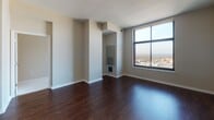 Located at 11215 Georgia Ave in Silver Spring, Maryland, this well-appointed high-rise unit offers a thoughtfully designed single-floor layout with a mix of stylish finishes and functional spaces. The open-concept living and dining area features rich, dark hardwood flooring and large floor-to-ceiling windows that flood the space with natural light while providing sweeping panoramic views of the Silver Spring skyline and surrounding landscape. A built-in media niche adds a distinctive architectural detail to the main living area. The kitchen is outfitted with dark espresso cabinetry, granite countertops, stainless steel appliances including a refrigerator, range, and dishwasher, and a decorative mosaic tile backsplash that adds a contemporary touch. The bedrooms are finished with plush wall-to-wall carpeting and feature large windows that continue the theme of abundant natural light and elevated city views. The bathrooms are clean and modern, featuring tile flooring, soaking tubs with tiled surrounds, granite-topped dark vanities, and chrome fixtures. The neutral color palette throughout the unit creates a bright, cohesive ambiance that complements both the interior finishes and the expansive urban views beyond.
