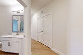 This thoughtfully designed single-story home in Georgetown, Texas offers a clean, modern aesthetic across two bedrooms and two bathrooms. Light wood-look flooring flows consistently throughout the space, creating a warm and cohesive feel from room to room. The open kitchen is a standout feature, showcasing two-tone cabinetry with taupe lower cabinets and white uppers, white quartz countertops, a subway tile backsplash, a center island with an undermount sink, and a full suite of stainless steel appliances including a refrigerator, range, microwave, and dishwasher. A globe pendant light and natural light from multiple windows brighten the kitchen area. The living area features recessed lighting and a ceiling fan, with built-in shelving adding functional character. The spacious primary bedroom includes a ceiling fan and ample room for furnishings. Both bathrooms are finished with white shaker-style cabinetry, white quartz vanity tops, framed mirrors, and brushed nickel fixtures. The primary bath includes a glass-enclosed shower with marble-look tile surround. Hallways are clean and well-lit, with a closet providing additional storage. The overall design is bright, modern, and move-in ready.