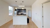 This well-appointed single-story, 3-bedroom, 3-bathroom home offers a thoughtfully designed layout that balances comfort and functionality. The open-concept kitchen serves as the heart of the home, showcasing dark espresso cabinetry, granite countertops, and a full suite of stainless steel appliances including a refrigerator, electric range, and microwave. A central island with pendant lighting above provides additional counter space and a natural gathering point, all set atop light hardwood-style flooring that extends into the living areas. Large windows allow natural light to fill the main living space, creating a bright and airy atmosphere. Each of the three bedrooms features plush carpeting and window blinds, with several rooms benefiting from multiple windows that invite additional natural light. The neutral wall tones throughout provide a clean, versatile backdrop. The three bathrooms are finished with clean white surrounds, soaking tub-shower combinations, curved shower rods, and chrome fixtures, offering a consistent and practical design. The overall aesthetic of this home is clean and modern, with a neutral palette that provides an excellent foundation for personalization.