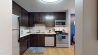 Located at 1180 Cushing Circle in Saint Paul, Minnesota, this single-floor, 2-bedroom, 2-bathroom residence offers a thoughtfully designed layout with a comfortable and functional flow throughout. The open-concept living and dining area serves as the heart of the home, featuring plush carpeting, a bold blue accent wall, and a large window that fills the space with natural light and views of lush greenery. The kitchen is efficiently appointed with rich dark cabinetry, light stone-style countertops, stainless steel appliances including a refrigerator, range, microwave, and dishwasher, and warm hardwood-style flooring. The spacious primary bedroom features carpet, a natural light-admitting window, and a closet with built-in organization. The second bedroom is equally comfortable. Both bathrooms are finished with dark wood vanities and classic white tile flooring; one features a tub-shower combo and the other a walk-in shower. Additional highlights include in-unit laundry, four closets providing generous storage, and a hallway connecting all areas seamlessly. The overall ambiance is warm and welcoming, combining practical design with stylish finishes throughout.
