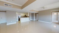 This well-appointed 2-bedroom, 2-bathroom residence offers a generous and thoughtfully designed single-floor layout. The expansive open-concept living and dining area is anchored by gleaming large-format porcelain tile flooring that reflects light beautifully, creating a bright and airy atmosphere. A tray ceiling with crown molding adds architectural depth to the main living space, which also features a stylish chandelier and ceiling fan for comfort and elegance.

The kitchen is a standout feature, showcasing crisp white cabinetry with glass-front upper panels, granite countertops, stainless steel appliances including a French door refrigerator, and a peninsula that flows seamlessly into the living area. Recessed lighting illuminates the space efficiently.

Both bedrooms are generously sized and finished with plush carpeting, crown molding, and ceiling fans. Natural light enters through windows, adding warmth to each room.

The two bathrooms each offer distinct character. The primary bathroom features a dual-sink vanity with white quartz countertops, marble-tiled walls, and a frameless glass walk-in shower. The secondary bathroom includes a white vanity, subway-tiled shower enclosure with a sliding glass door, and a bright, clean aesthetic throughout. This residence combines comfort, functionality, and refined finishes in a cohesive design.