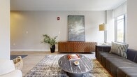 Located at 48–66 W Broad St in Rochester, NY, this 650-square-foot single-floor apartment offers a thoughtfully designed layout combining modern aesthetics with functional living. The open-concept kitchen and living area serves as the heart of the unit, showcasing a contemporary kitchen with wood-toned cabinetry, white subway tile backsplash, white quartz countertops, stainless steel appliances including a dishwasher and refrigerator, and a kitchen island for additional prep space. Light wood-style flooring runs throughout, creating a cohesive and airy feel. The living area is bright and inviting, featuring large windows that offer urban views of Rochester's downtown architecture, including a striking historic church tower. Natural light flows generously through the space, enhancing its open ambiance. The bedroom provides a comfortable retreat with continued light flooring and easy access to the bathroom. The bathroom is clean and modern, featuring a walk-in glass-enclosed shower with white subway tile, tile flooring, and a vanity. The overall design balances contemporary finishes with a warm, neutral palette, creating a stylish and comfortable urban living experience.