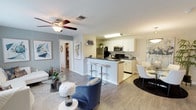 This single-floor residence offers a thoughtfully designed open-concept layout that seamlessly connects the living, dining, and kitchen areas. The living room features light wood-style flooring, a ceiling fan, and large windows that invite natural light and outdoor views, creating a bright and welcoming atmosphere. A peninsula counter with bar seating bridges the kitchen and living space, making it ideal for entertaining.

The kitchen is outfitted with white cabinetry, dark countertops, and stainless steel appliances, including a refrigerator, microwave, and electric range. Light tile flooring runs throughout this space, complementing the clean, contemporary aesthetic.

The bedroom is generously sized, featuring a ceiling fan, large windows with views of greenery, and wood-style flooring. A standout walk-in closet provides ample storage with wire shelving on multiple walls. Two full bathrooms each include a tub-shower combination, white vanity cabinetry, and dark countertops finished with tile flooring.

A flexible secondary living area offers additional functional space. The dedicated in-unit laundry room includes a full-size washer and dryer, wire shelving, and a distinctive oval window, adding both practicality and a unique architectural detail.