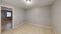 Located at 4759 NW Motif Manor Blvd in Lawton, Oklahoma, this single-floor, one-bedroom, one-bathroom unit offers a practical and efficient layout. Light beige tile flooring runs throughout the entire space, providing a cohesive and easy-to-maintain surface. The open-concept living, dining, and kitchen area forms the heart of the unit, with a central half-wall partition defining the kitchen zone. The galley-style kitchen is outfitted with dark navy cabinetry on both upper and lower levels, light granite-style countertops, a stainless steel sink, and a white electric range, creating a bold contrast that anchors the space. The bedroom is a comfortable, naturally lit room featuring a window with blinds and a flush-mount ceiling light. Adjacent to the bedroom is a walk-in closet equipped with dual shelving units along the walls, offering generous storage capacity and housing the electrical panel. The bathroom includes a tiled tub/shower surround with built-in niche shelving, a white vanity with cabinet storage, and tile flooring that mirrors the rest of the unit. Throughout the space, neutral gray walls, white baseboards, and flush-mount ceiling fixtures contribute to a clean, understated aesthetic suited to a variety of décor styles.