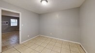 Located at 4759 NW Motif Manor Blvd in Lawton, Oklahoma, this single-floor, one-bedroom, one-bathroom unit offers a practical and efficient layout. Light beige tile flooring runs throughout the entire space, providing a cohesive and easy-to-maintain surface. The open-concept living, dining, and kitchen area forms the heart of the unit, with a central half-wall partition defining the kitchen zone. The galley-style kitchen is outfitted with dark navy cabinetry on both upper and lower levels, light granite-style countertops, a stainless steel sink, and a white electric range, creating a bold contrast that anchors the space. The bedroom is a comfortable, naturally lit room featuring a window with blinds and a flush-mount ceiling light. Adjacent to the bedroom is a walk-in closet equipped with dual shelving units along the walls, offering generous storage capacity and housing the electrical panel. The bathroom includes a tiled tub/shower surround with built-in niche shelving, a white vanity with cabinet storage, and tile flooring that mirrors the rest of the unit. Throughout the space, neutral gray walls, white baseboards, and flush-mount ceiling fixtures contribute to a clean, understated aesthetic suited to a variety of décor styles.