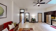Located at 50 W 4th St in the heart of downtown Winston-Salem, NC, this well-appointed 2-bedroom, 2-bathroom unit offers a thoughtfully designed single-level floor plan. The open-concept living and dining area is anchored by light hardwood flooring, crisp white walls, and notable ceiling height that creates an airy, spacious feel. A ceiling fan with integrated lighting adds both function and style, while bold black door and window trim provide a contemporary contrast throughout. Transom windows positioned above interior doorways further enhance the sense of openness and allow light to flow between spaces. The kitchen features rich dark cabinetry, stainless steel appliances including a full-size refrigerator, and ample counter and storage space. Both bathrooms are outfitted with modern glass vessel sinks set on dark vanities, framed mirrors, and shower-tub combinations. The primary bedroom is generously sized with light wood floors and a clerestory-style window, while the second bedroom enjoys a window with views of the surrounding downtown architecture. A connecting hallway ties the layout together efficiently, making this a functional and stylish urban residence in the heart of Winston-Salem's city center.