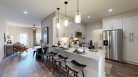 Located at Treesort View in Gainesville, Georgia, this single-floor residence offers a thoughtfully designed layout with modern finishes and a cohesive contemporary aesthetic. The open-concept kitchen serves as a central highlight, featuring white shaker cabinetry, granite countertops, a subway tile backsplash, and stainless steel appliances including a range and over-the-range microwave. A peninsula with pendant lighting and bar seating connects the kitchen seamlessly to the dining and living areas, creating an inviting space for both everyday living and entertaining. The living room is bright and comfortable, with large windows that allow generous natural light, wood-look flooring, and a ceiling fan overhead. The space flows naturally between relaxed seating arrangements and a dedicated media area. The bedrooms are well-proportioned, each featuring ceiling fans, large windows with blinds and curtain panels, and wood-look flooring. The bathroom includes a full tub-shower combination, granite-topped vanity with white cabinetry, and coordinating hardware. A laundry area with a washer and dryer is also present within the unit. Throughout the residence, neutral wall tones, consistent flooring, and dark accent hardware create a polished, move-in-ready environment.