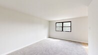 Located at 4838 Pulaski Ave in Philadelphia's 19144 zip code, this one-bedroom, one-bathroom single-floor unit offers a clean, functional layout with a well-defined flow between spaces. The interior is finished with neutral white walls and light gray carpet throughout the living and sleeping areas, creating a bright and cohesive aesthetic. The living room provides a comfortable open area with a warm, understated feel. The kitchen is thoughtfully positioned within the floorplan and features wood-style flooring, white cabinetry, and standard appliances including a gas range and sink, offering a practical cooking space. The generously sized bedroom is carpeted and filled with natural light through a dark-framed multi-pane window that frames views of surrounding greenery. Three closets throughout the unit provide ample storage, a notable feature for a space of this size. The bathroom includes a full-size soaking tub with a bright white surround, maintaining a clean and simple design. A hallway connects the rooms efficiently, contributing to the unit's organized and easy-to-navigate layout. Overall, this space presents a well-maintained, move-in-ready environment suited for comfortable everyday living.