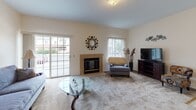 Located at 100 Wind Willow Way in Rochester, NY, this single-floor residence offers a well-organized and comfortable layout designed for everyday living. The living room serves as the heart of the home, anchored by a tile-surround fireplace and complemented by a sliding glass door that invites natural light and provides views of the surrounding neighborhood. The open feel of the space is enhanced by plush carpeting and a seamless connection to the adjacent dining area, which features vaulted ceiling accents and an elegant chandelier overhead — ideal for both casual meals and formal gatherings. The galley-style kitchen is efficiently designed with warm wood cabinetry, ample counter space, and a full suite of appliances including a range, refrigerator, and dishwasher. A pass-through connects the kitchen to the living area, promoting an open flow throughout. The bedroom is generously sized, offering carpeted floors, a large window with vertical blinds, and a spacious walk-in closet with built-in shelving. The full bathroom is clean and well-appointed with a vanity, mirror with overhead lighting, and a shower-tub combination. A dedicated laundry room with side-by-side washer and dryer units, wire shelving, and tile flooring adds a practical and convenient finishing touch to this thoughtfully laid-out home.