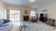 Located at 100 Wind Willow Way in Rochester, NY, this single-floor residence offers a well-organized and comfortable layout designed for everyday living. The living room serves as the heart of the home, anchored by a tile-surround fireplace and complemented by a sliding glass door that invites natural light and provides views of the surrounding neighborhood. The open feel of the space is enhanced by plush carpeting and a seamless connection to the adjacent dining area, which features vaulted ceiling accents and an elegant chandelier overhead — ideal for both casual meals and formal gatherings. The galley-style kitchen is efficiently designed with warm wood cabinetry, ample counter space, and a full suite of appliances including a range, refrigerator, and dishwasher. A pass-through connects the kitchen to the living area, promoting an open flow throughout. The bedroom is generously sized, offering carpeted floors, a large window with vertical blinds, and a spacious walk-in closet with built-in shelving. The full bathroom is clean and well-appointed with a vanity, mirror with overhead lighting, and a shower-tub combination. A dedicated laundry room with side-by-side washer and dryer units, wire shelving, and tile flooring adds a practical and convenient finishing touch to this thoughtfully laid-out home.