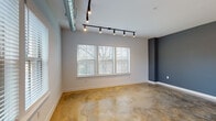 This single-floor studio unit in Memphis, Tennessee showcases a distinctive industrial-modern aesthetic that blends raw architectural elements with refined finishes. Polished concrete floors extend throughout the entire space, offering a warm, variegated tone that anchors the overall design. Exposed cylindrical ductwork runs along the ceiling, complemented by track lighting that provides adjustable, directional illumination across each area.

The open main living area features multiple windows fitted with white horizontal blinds, allowing generous natural light to fill the space. A deep slate-blue accent wall adds a bold visual contrast to the otherwise neutral gray palette, lending depth and character to the room.

The kitchen runs along one wall in a galley-style configuration, featuring dark espresso cabinetry, granite countertops, and a full suite of stainless steel appliances including a refrigerator, range, microwave, and dishwasher. A window above the sink area draws in additional natural light.

The bathroom is cleanly finished with a dark wood vanity, granite countertop, an oversized mirror, and tile flooring. The unit's compact, efficiently designed floor plan makes thoughtful use of every area, creating a cohesive and contemporary living environment.