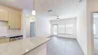 This single-story residence offers three bedrooms and two bathrooms within a well-organized, efficiently designed floor plan. The open-concept living and kitchen area forms the heart of the home, where light hardwood-style flooring, a textured ceiling, and a ceiling fan contribute to a clean, contemporary atmosphere. A sliding glass door and dual windows flood the living space with natural light, enhancing its airy feel.

The kitchen is outfitted with light wood cabinetry, stainless steel appliances including a refrigerator, range, microwave, and dishwasher, and a granite-topped island with pendant lighting overhead. The layout promotes easy interaction between the kitchen and living areas.

The bedrooms feature neutral carpet flooring and ceiling fans, with windows fitted with horizontal blinds. The primary bedroom connects to a well-appointed bathroom featuring a dual-sink vanity with granite countertops, light wood cabinetry, a large framed mirror, and hardwood-style flooring. A walk-in closet with wire shelving provides ample storage.

A dedicated laundry room houses a full-size washer and dryer. Throughout, the consistent use of neutral tones and modern fixtures creates a cohesive, move-in ready environment.