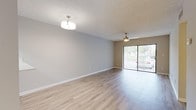This single-floor residence offers a thoughtfully designed layout with a clean, contemporary aesthetic throughout. The open living area is finished with light-toned laminate wood flooring, neutral gray walls, and a textured ceiling, creating a bright and welcoming atmosphere. A ceiling fan provides comfort, while a sliding glass door floods the space with natural light and offers views of lush greenery outside.

The galley-style kitchen is efficiently arranged with gray shaker-style cabinetry, white countertops, and tile flooring. It is fully equipped with stainless steel appliances, including a refrigerator, electric range, and over-the-range microwave, along with a double-basin sink — providing everything needed for daily cooking.

The bedrooms are generously sized, each featuring light laminate flooring, neutral tones, and windows with vertical blinds that allow for adjustable natural light. Both bedrooms are accompanied by walk-in closets outfitted with wire shelving systems, offering ample and well-organized storage space.

The bathroom is finished with tile flooring, a gray vanity with a framed mirror, and a full tub-shower combination, maintaining the clean and modern character found throughout the home. Louvered closet doors add a classic touch to the overall design. The unit presents a move-in ready, functional living environment.