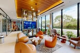 Located at 776 Riverside Dr in Coral Springs, FL, this single-floor amenity space offers a generously proportioned, thoughtfully designed environment ideal for both collaboration and relaxation. The interior immediately impresses with its warm wood-paneled ceilings, light hardwood flooring, and expansive floor-to-ceiling windows that flood the space with natural light and provide lush, verdant views of the surrounding landscape.

The main lounge area is anchored by a striking built-in shelving unit with curated décor and an integrated flat-screen display. Curved, cognac-leather lounge chairs and organic natural wood accent tables create an inviting, contemporary atmosphere. A sculptural sputnik chandelier adds an artistic focal point overhead.

A dedicated conference area features a stunning live-edge wood table surrounded by ergonomic seating, illuminated by clustered pendant lights and bordered by floor-to-ceiling glass walls that maintain openness while offering privacy. An additional wet bar and kitchenette area, accented by a bold "Think About Things Differently" mural, provides convenient refreshment access. The glass-partitioned entry vestibule offers a clean, modern welcome, completing this well-appointed, multifunctional space.