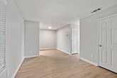 This 2-bedroom, 2-bathroom unit is thoughtfully laid out across a single floor, offering a practical and comfortable living environment. The living area features light wood-look flooring, neutral gray walls, and a textured ceiling, with windows dressed in horizontal blinds that allow natural light to filter through. The space flows openly toward the kitchen and hallway, creating a connected feel throughout.

The kitchen is equipped with black appliances, including a full-size refrigerator and electric range, complemented by light gray cabinetry and wood-look flooring that ties seamlessly to the rest of the unit.

Both bedrooms are carpeted and include ceiling fans with light fixtures, closets, and windows with blinds. The primary bedroom features a walk-in style closet, while the second bedroom offers a comparable layout with its own closet and natural light.

The two bathrooms are finished with light wood-look flooring, granite-style countertops on the vanities, and neutral wall tones. One bathroom includes a tub/shower combination, while the other features a more compact design.

Additional spaces include a hallway connecting the main rooms and a utility room for added functionality. Throughout, the unit maintains a clean, neutral palette that provides a versatile backdrop for a variety of living arrangements.