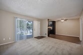 Located in San Diego's 92119 neighborhood, this single-floor, one-bedroom, two-bathroom home offers a well-organized layout across a comfortable footprint. The living room features a mix of hardwood and carpeted flooring beneath a textured ceiling, creating a warm and inviting atmosphere, while a sliding glass door fills the space with natural light and provides direct access to a private patio overlooking greenery. The combined dining and kitchen area is a standout feature, showcasing a galley-style design with rich dark cabinetry, granite-style countertops, a double-basin sink, and a full suite of stainless steel appliances including a refrigerator, electric range, microwave, and dishwasher — all set atop light wood-look flooring. The generously sized primary bedroom is carpeted and includes a built-in closet with shelving, along with a second closet for additional storage. Two full bathrooms serve the home; one includes a dark-cabinet vanity with stone-style countertop and a tub/shower combo with a bright window above, while the other provides additional convenience. Neutral tones and a clean, modern finish throughout give the home a move-in-ready feel.