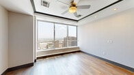 Located in the heart of downtown Dallas on N Field Street, this well-appointed one-bedroom, one-bathroom residence offers a thoughtfully designed open-concept layout. The combined kitchen and living area serves as the central hub of the space, showcasing wide-plank hardwood flooring, recessed lighting, and expansive floor-to-ceiling windows that flood the interior with natural light while framing impressive panoramic views of the Dallas skyline. The kitchen is a standout feature, equipped with stainless steel appliances, dual-tone blue-gray cabinetry, a white geometric tile backsplash, and a generously sized island topped with striking veined quartz countertops — ideal for both cooking and entertaining. The spacious bedroom continues the floor-to-ceiling window theme, with plush carpeting, a ceiling fan, and sweeping city views that make it a serene retreat. The walk-in closet offers multi-level shelving and hanging rails for well-organized storage. The bathroom features a frameless glass-enclosed walk-in shower adorned with large-format travertine-style tile, hexagonal floor tiles, and a built-in bench. A dedicated laundry area with an in-unit washer completes the functional layout of this polished urban residence.