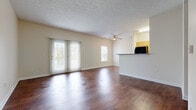 Located at 3995 Cracker Cove Ln in Canal Winchester, Ohio, this single-floor, 4-bedroom, 1-bathroom home offers a practical and comfortable layout. The open-concept living room is a standout feature, showcasing rich, dark hardwood-style flooring that extends throughout the common areas. Natural light pours in through sliding glass doors fitted with vertical blinds, offering outdoor views and brightening the space. A ceiling fan adds to the room's comfort, while a textured ceiling adds architectural character overhead. The kitchen is efficiently laid out with warm wood cabinetry, ample counter space, and full appliances including a refrigerator, range, and overhead microwave, all finished in a cohesive style. It opens conveniently to the living area via a pass-through counter. The four bedrooms feature plush wall-to-wall carpeting and windows that bring in natural light. At least one bedroom includes a closet with built-in wire shelving for practical storage. The full bathroom is well-appointed with a single-sink vanity featuring wood cabinetry, a full mirror, and a tub/shower combination, all finished with matching hardwood-style flooring. Neutral tones and clean white trim throughout create a cohesive, move-in-ready aesthetic.