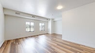 Located at 1120 S Walton Blvd in Bentonville, Arkansas, this single-floor unit offers a clean, modern design with a bright and open layout. The main living area features warm wood-look laminate flooring that flows throughout, crisp white walls, and multiple windows fitted with horizontal blinds that allow natural light to fill the space. The open floor plan provides a generous and flexible living area with a distinct sense of spaciousness.

The kitchen is well-appointed with white upper cabinetry, sage-toned lower cabinets, white countertops, and stainless steel appliances including a refrigerator, dishwasher, and microwave. A stainless steel sink with a modern pull-down faucet completes the functional workspace.

The bathroom is designed with accessibility in mind, featuring a floating vanity with an integrated sink, a large mirror with overhead lighting, neutral square tile flooring, and a grab bar along the wall. The room connects conveniently to the main living space through a frosted glass door.

A dedicated in-unit laundry area houses a stacked washer and dryer, adding a practical convenience within the unit. The bedroom area benefits from vaulted ceiling details and a large window that invites natural light and outdoor views, creating a calm and airy retreat. Overall, the unit presents a cohesive, modern aesthetic suited for comfortable everyday living.