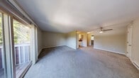 Located at 4455 NE 12th St in Renton, Washington, this two-bedroom, one-bathroom residence offers a straightforward single-floor layout designed for comfortable everyday living. The open living room is generously proportioned, featuring neutral-toned carpet, a ceiling fan, a baseboard heating system, and access to an outdoor balcony through a sliding glass door that allows natural light to fill the space. The kitchen is positioned adjacent to the living area and includes cabinetry and countertops, providing a functional workspace. Both bedrooms feature wall-to-wall carpet, textured ceilings, and baseboard heating. The primary bedroom includes a large sliding-door closet and a window overlooking lush greenery, lending a tranquil feel. The second bedroom also benefits from natural light and closet storage with frosted sliding doors. The full bathroom is finished with wood-look plank flooring, a white vanity with a dark countertop, a combination tub and shower, and neutral wall tones that create a clean, understated aesthetic. Throughout the residence, a consistent neutral color palette and practical finishes contribute to a cohesive and functional living environment.