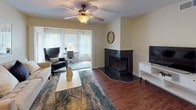 Located at 4949 Marbrisa Dr in Tampa, FL, this single-floor residence offers a thoughtfully designed layout with comfortable, functional living spaces throughout. The living room serves as a central gathering area, highlighted by a striking dark tile corner fireplace, warm wood-style flooring, and a ceiling fan. Natural light filters in through large windows dressed with decorative curtains, and the space flows seamlessly into an adjoining flex area ideal for a home office or den. The kitchen is well-equipped with stainless steel appliances — including a refrigerator, range, and over-the-range microwave — complemented by white cabinetry, granite-style countertops, and a tasteful tile backsplash. A separate dining area provides additional space for entertaining. The residence includes multiple bedrooms, each featuring plush carpeting, ceiling fans, ample closet space with bifold doors, and windows that invite natural light. Two bathrooms are appointed with white vanity cabinetry, granite-style countertops, framed mirrors, and shower/tub combinations. The overall ambiance is warm and inviting, with a neutral color palette, consistent finishes, and a layout that balances open communal areas with private, restful retreats.