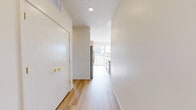 Located at 504 N 187th Ct in Elkhorn, Nebraska, this well-appointed 2-bedroom, 2-bathroom single-floor home showcases a clean, contemporary design with high-quality finishes throughout. The open-concept kitchen and living area serves as the heart of the home, anchored by a large center island with a white quartz countertop, gold-accented fixtures, and a deep undermount sink. Two pendant lights with brass hardware hang above the island, while stainless steel appliances, two-tone cabinetry combining white upper cabinets with natural wood lower cabinets, and light hardwood flooring complete the modern aesthetic. A large window and sliding glass door flood the space with natural light and provide outdoor views. The primary bedroom is generously sized, featuring hardwood floors, expansive windows overlooking a lush natural landscape, and an ensuite bathroom with a walk-in closet. The bathrooms are finished with warm wood vanities, gold hardware, sliding glass tub-shower enclosures, and light hardwood flooring. The secondary bedroom offers plush carpet, a ceiling fan, and windows with neighborhood views. Throughout the home, a neutral color palette, recessed lighting, and consistent gold accents create a cohesive, modern atmosphere.